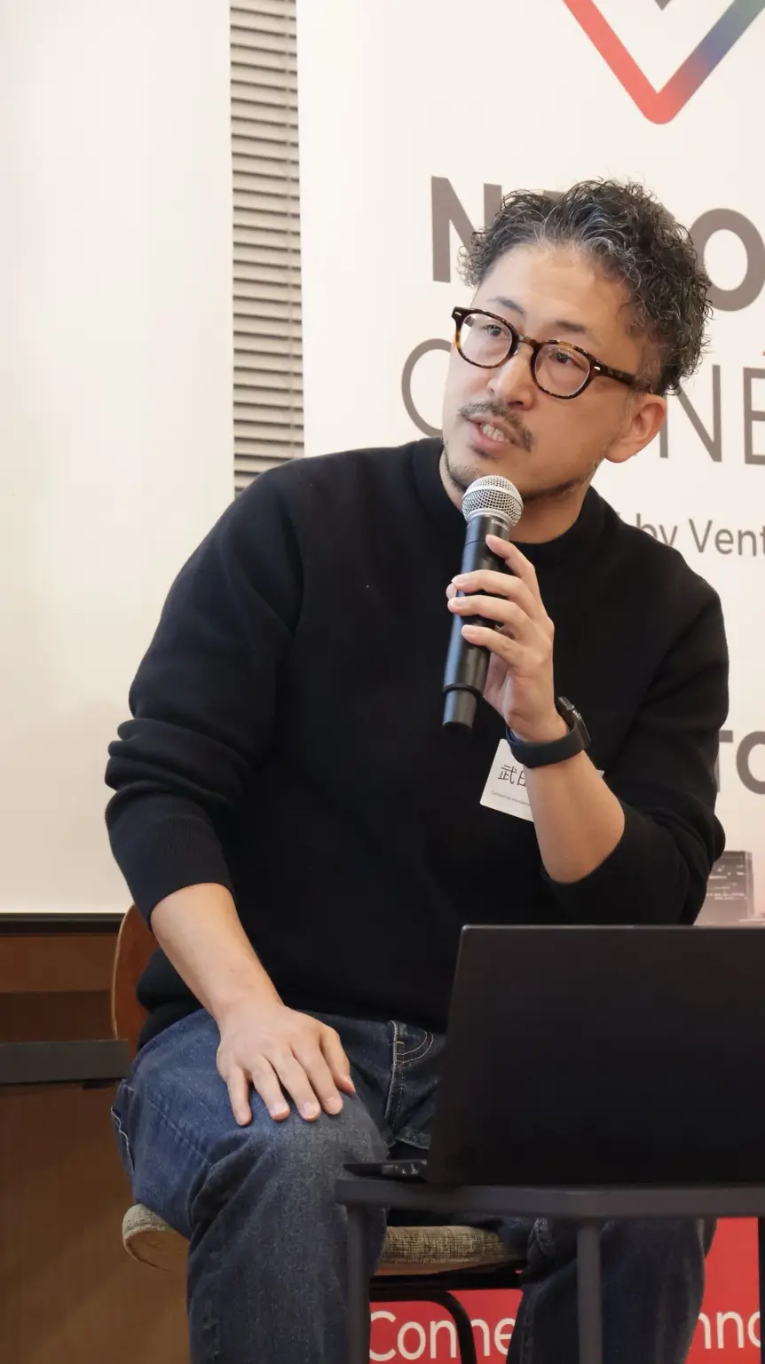 イベントに登壇し、マイクを持って話す武田優人